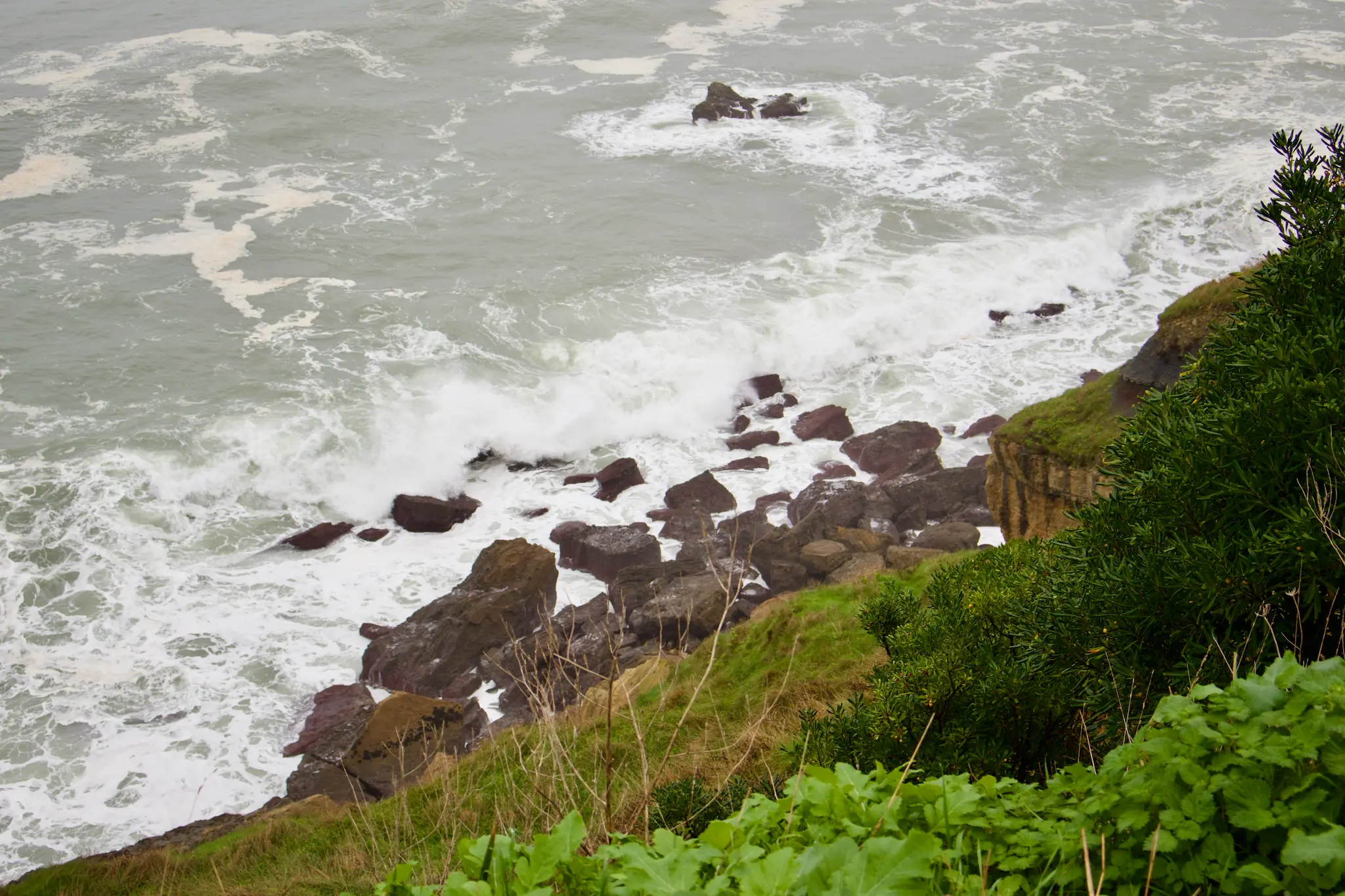 Vista en perspectiva desde lo alto del acantilado en el Cerro de Santa Catalina hacia el mar Cantábrico en Gijón