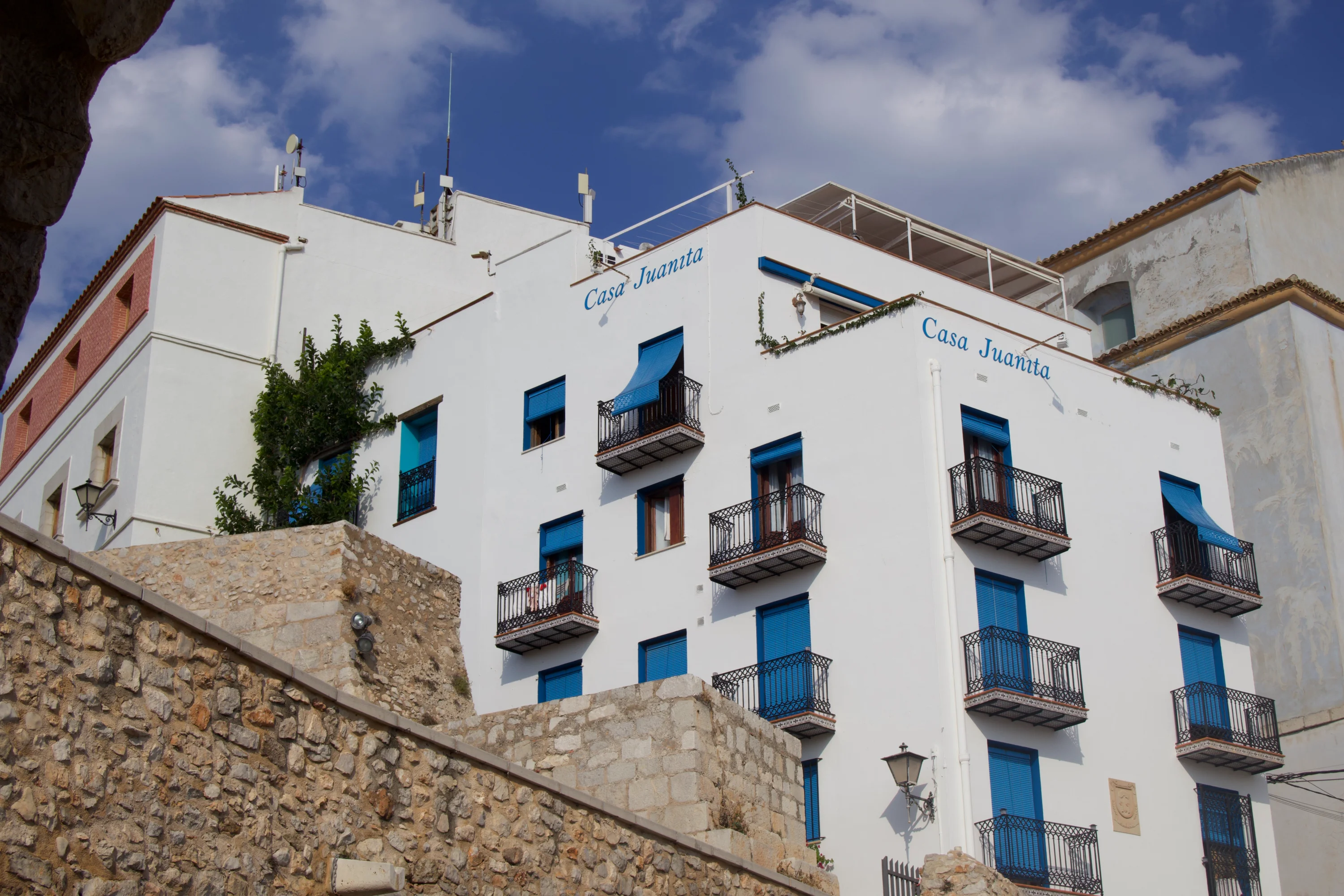 Casa Juanita, con sus balcones azules y paredes blancas, destaca entre las calles y muros de piedra en el corazón de Peñíscola.