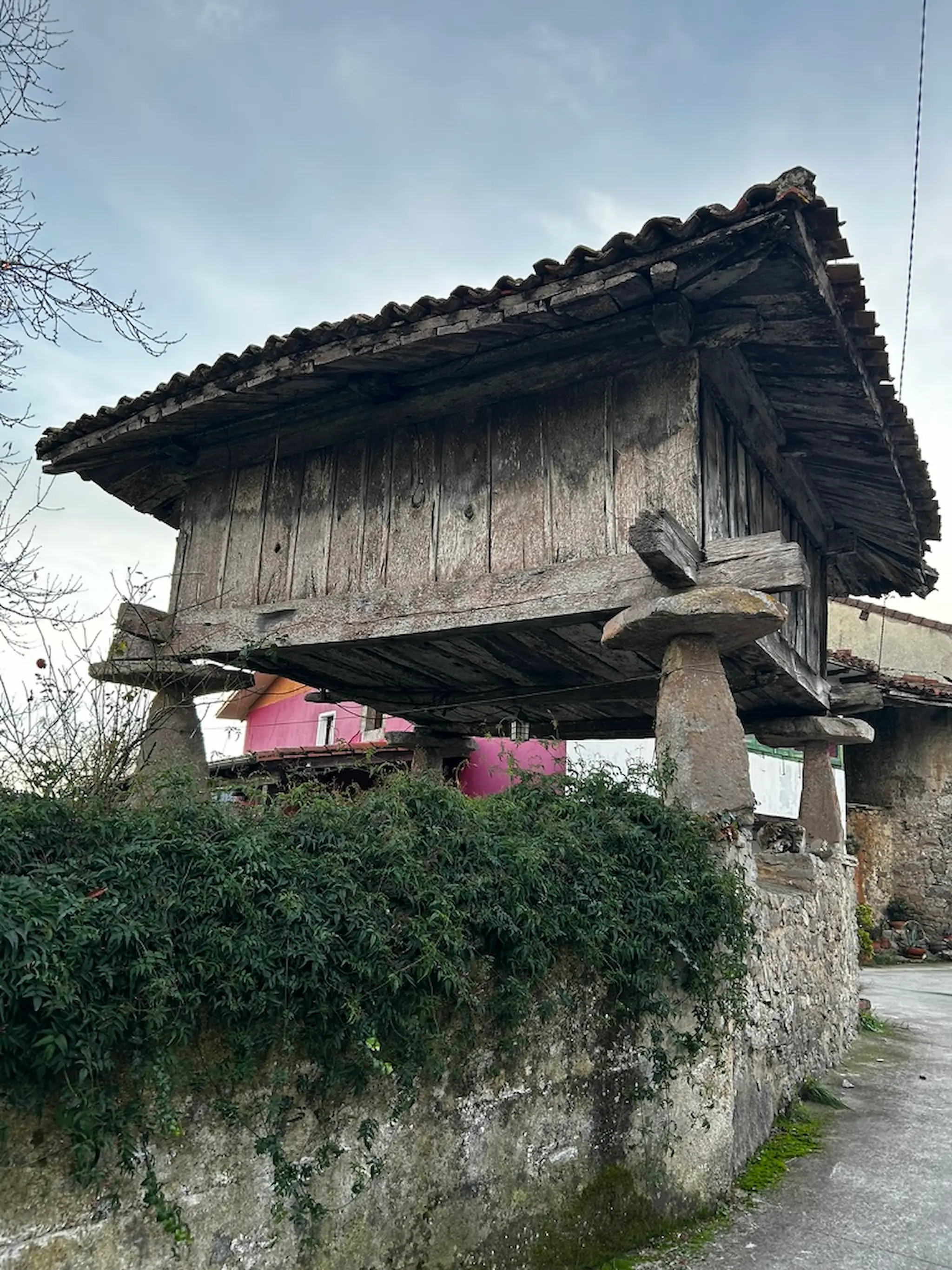 Hórreo tradicional de madera sobre pilares de piedra en un pueblo rural de Asturias