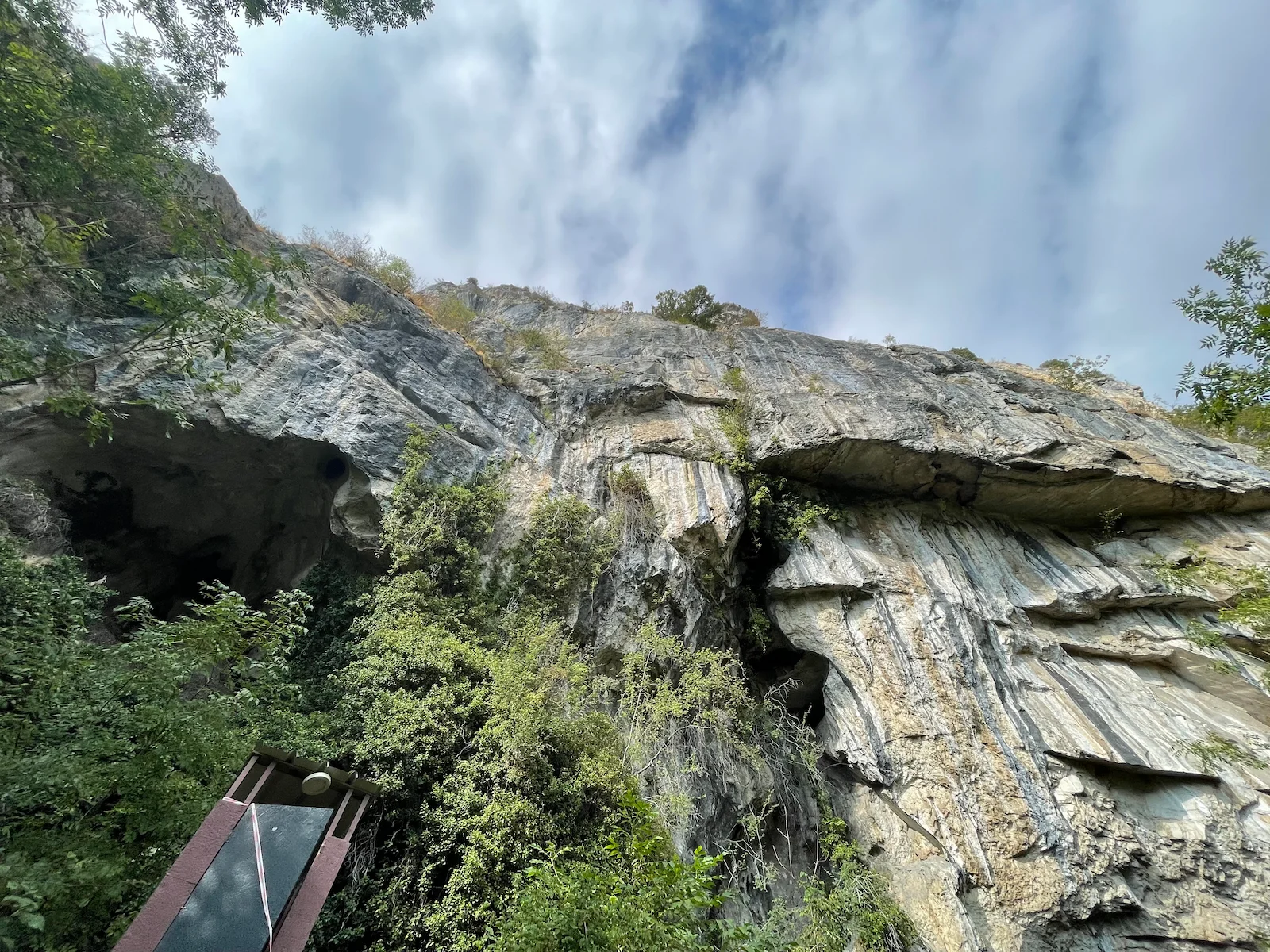 Vista desde abajo de la gran roca y vegetación en Quiès Calcaires, camino a una cueva en Ussat, Francia