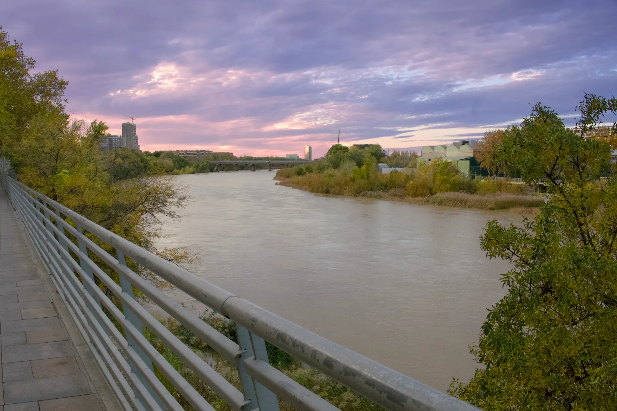 Perspectiva del río Ebro fluyendo junto al paseo bajo un cielo de nubes suaves al atardecer