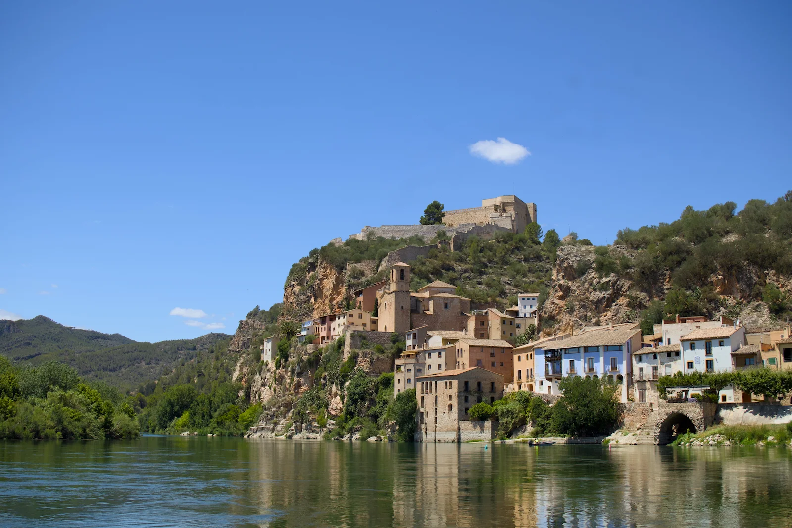 Vista del castillo y el río Ebro desde Miravet, con casas históricas al borde del agua