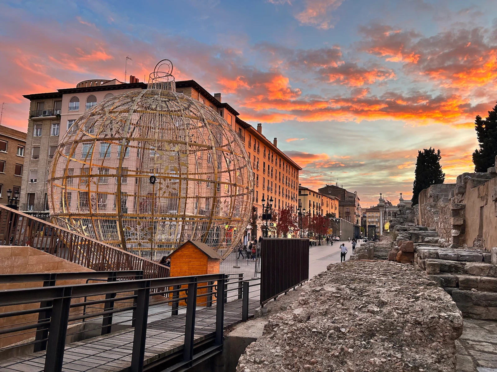 Pocas nubes a lo alto de Zaragoza, con un atardecer rojizo desde las calles y murallas